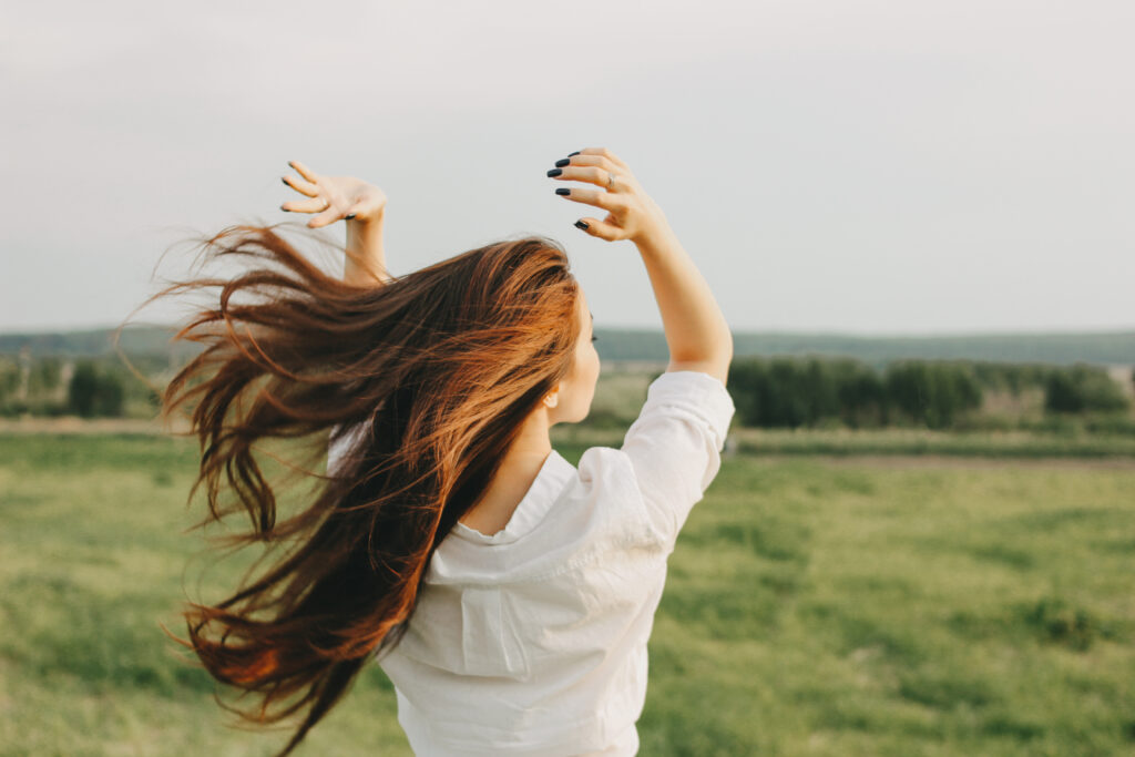 Woman with long healthy hair walking in a field – symbolizing natural hair care