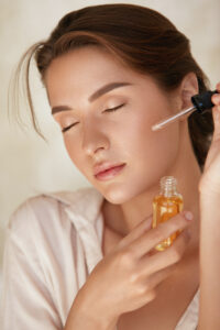 Woman applying facial oil with dropper – skincare for oily acne-prone skin