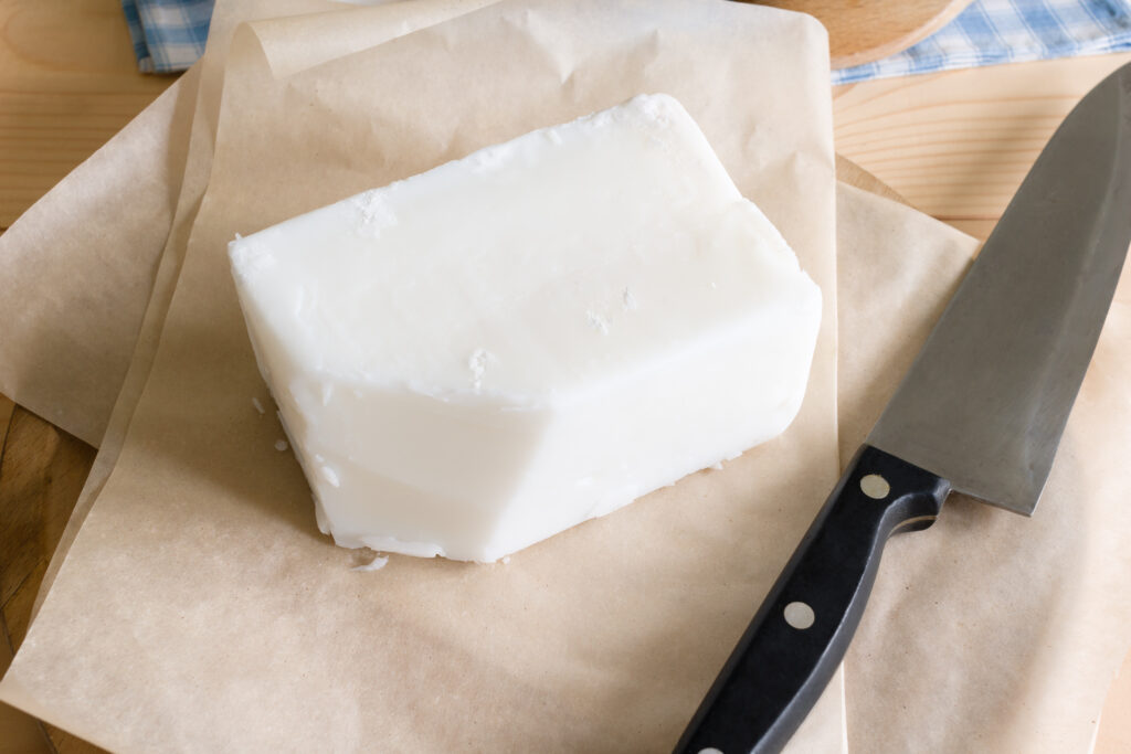 Rendered beef tallow blocks on a wooden surface, often used in traditional skincare formulations