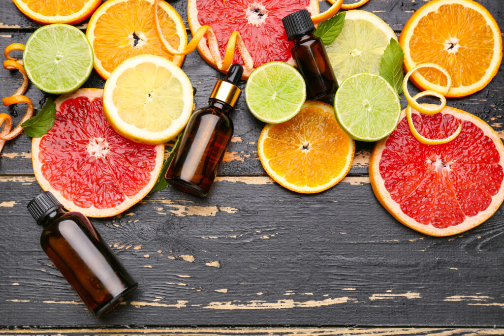 Cold-pressed citrus essential oils with fresh fruits on a dark wooden background