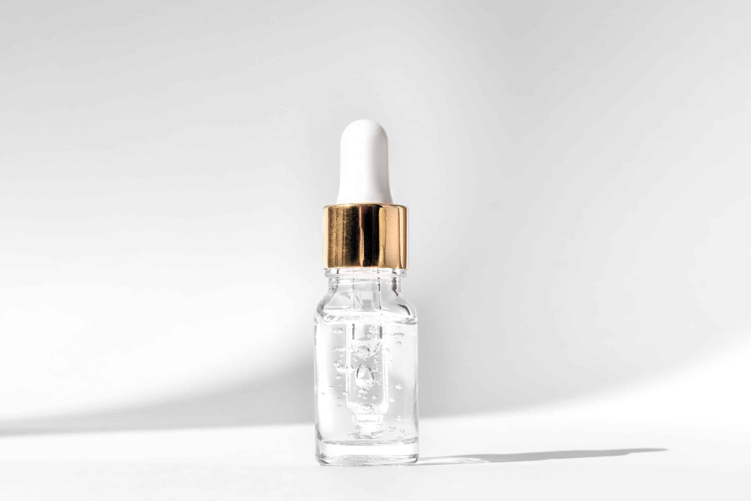 Clear niacinamide serum in glass bottle with dropper – skincare product photography on white background